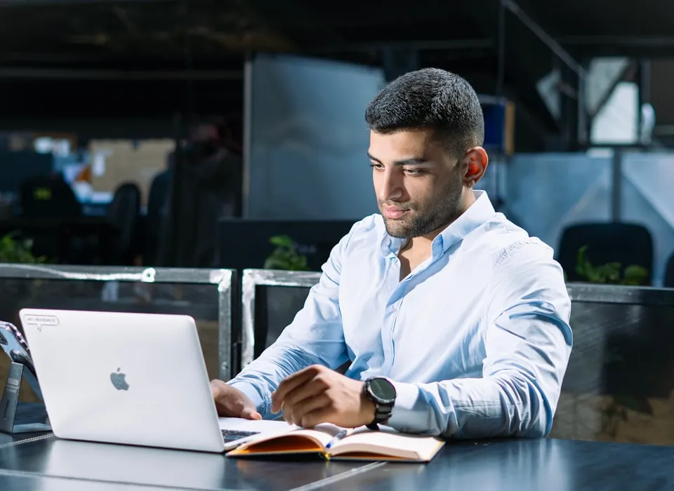 A man sitting at a table using a laptop computer